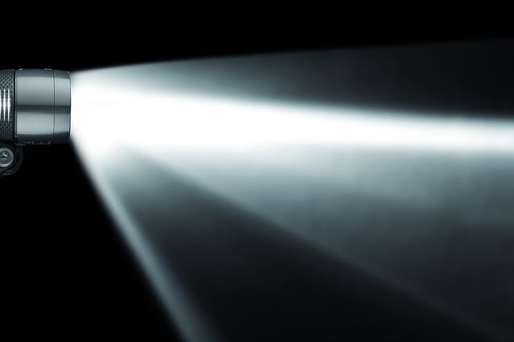 Einfach nur hell ist nicht alles - das Licht des Fahrradscheinwerfers muss auch gebündelt werden, um die Fahrbahn gut auszuleuchten. Ein Scheinwerfer von der Seite mit Lichtkegel, dessen obere Begrenzung fast parallel zum Boden verläuft.